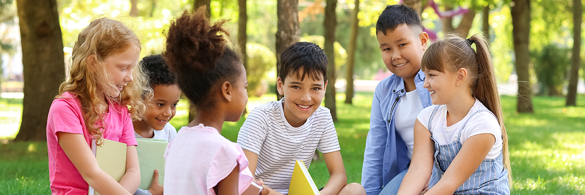 Group of six children sitting in nature and smiling